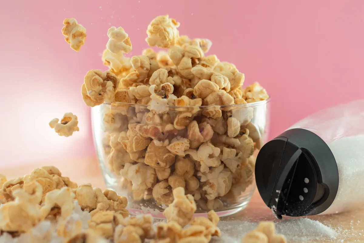 Fresh kettle corn tumbling above a full glass bowl