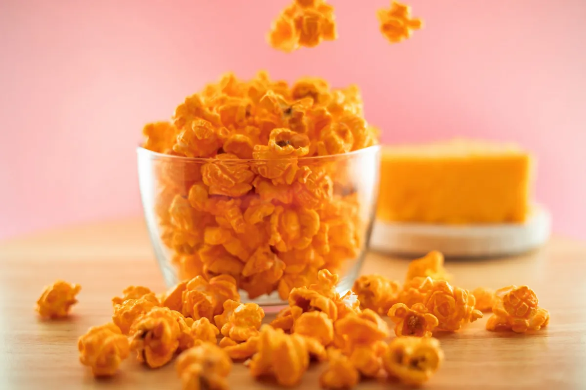 Bright cheddar popcorn in a clear bowl