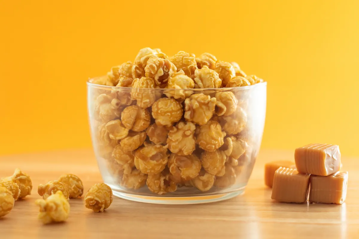 A glass bowl filled with golden caramel popcorn